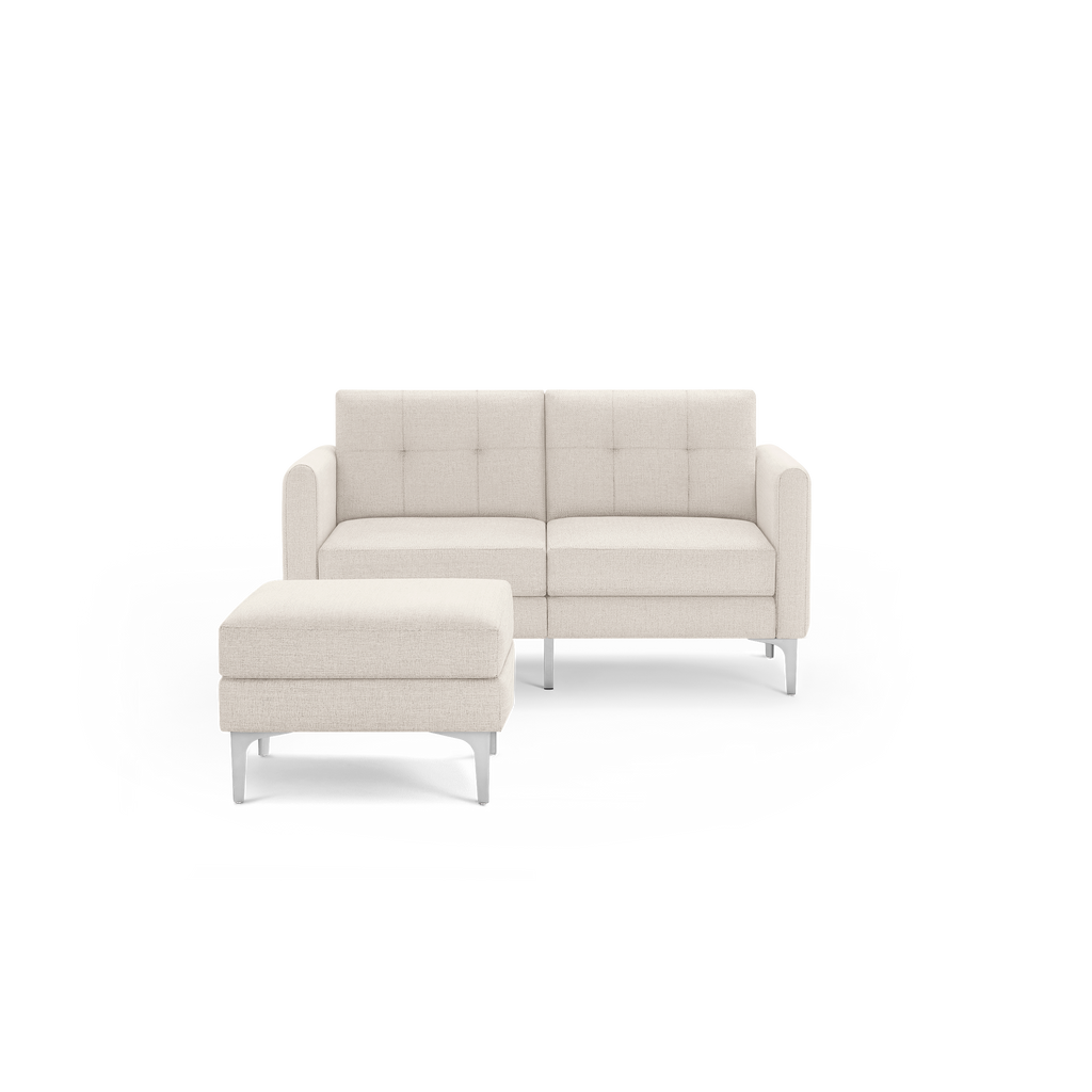 Modern beige fabric loveseat with tufted backrest and matching cushioned ottoman, both with sleek metal legs.