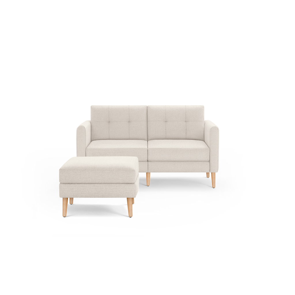 Beige modern two-seater sofa with button-tufted cushions and matching ottoman, featuring wooden legs and clean design.