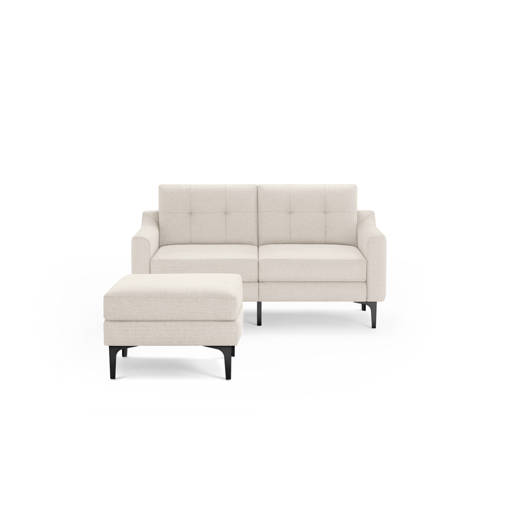 Beige two-seater sofa with tufted back cushions and matching ottoman, both featuring black legs.