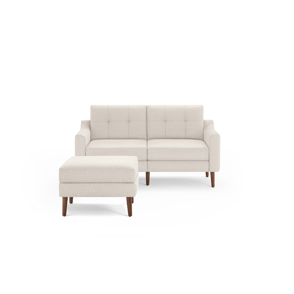 Beige upholstered mid-century modern loveseat with tufted backrest and matching ottoman, featuring wooden tapered legs.