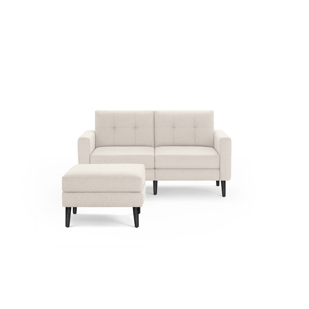 Compact beige fabric loveseat sofa with tufted back cushions and matching cushioned ottoman, featuring black wooden legs.