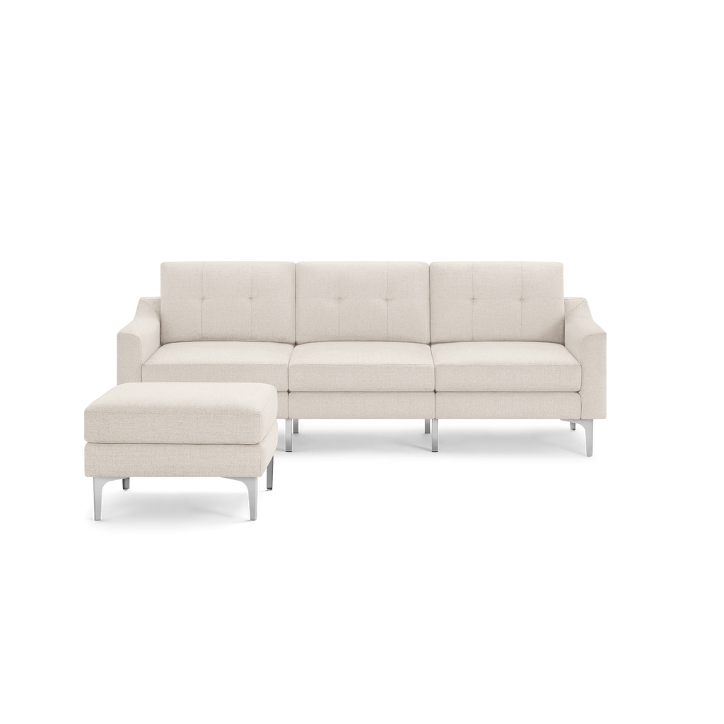 Light beige sectional sofa with tufted cushions and matching ottoman, supported by sleek silver legs.