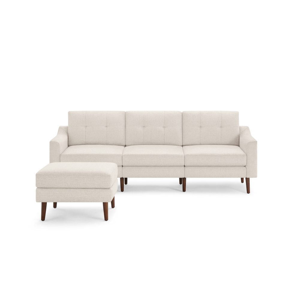 Modern beige sectional sofa with tufted back cushions and matching ottoman, featuring wooden legs and clean lines.