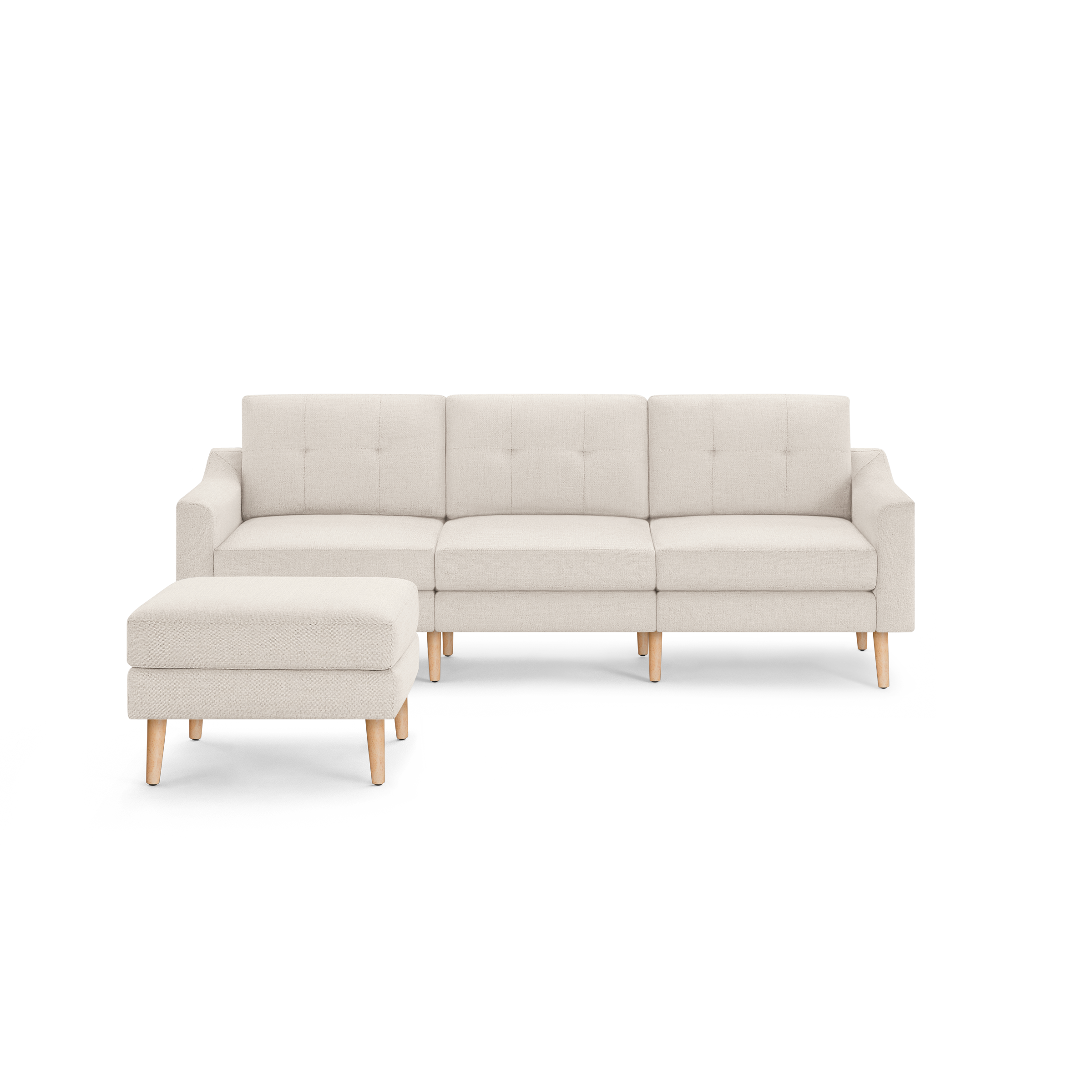Light beige fabric sectional sofa with tufted back cushions and matching ottoman, supported by light wooden legs.