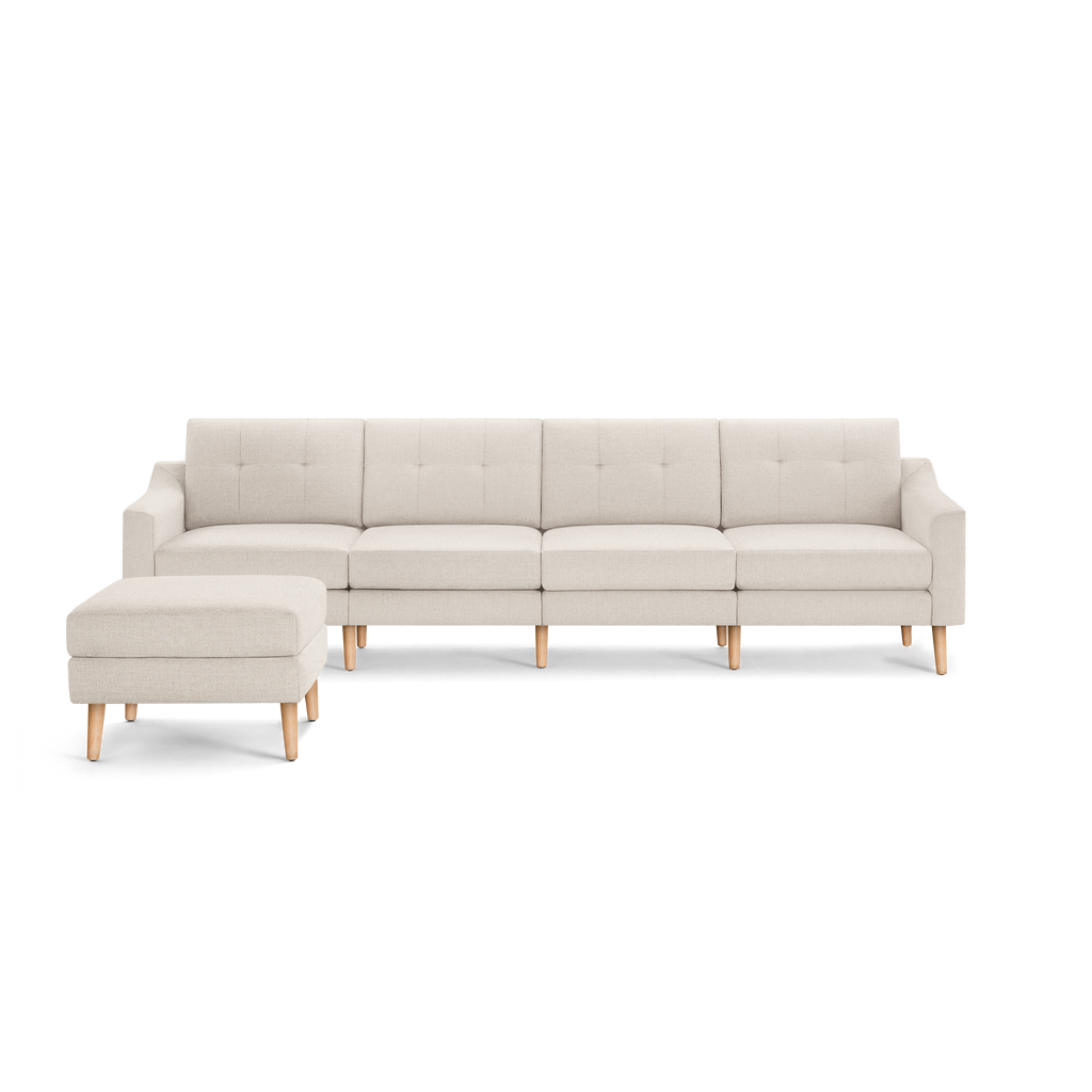 Beige L-shaped sectional sofa with tufted cushions and light wooden legs, including a matching ottoman on the left side.