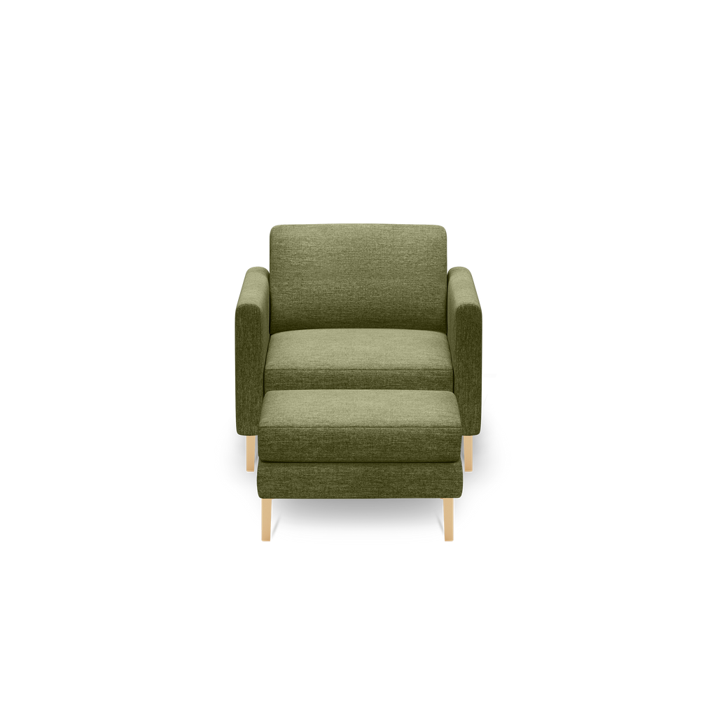 Green upholstered armchair with wooden legs and a pull-out footrest, shown against a black background.