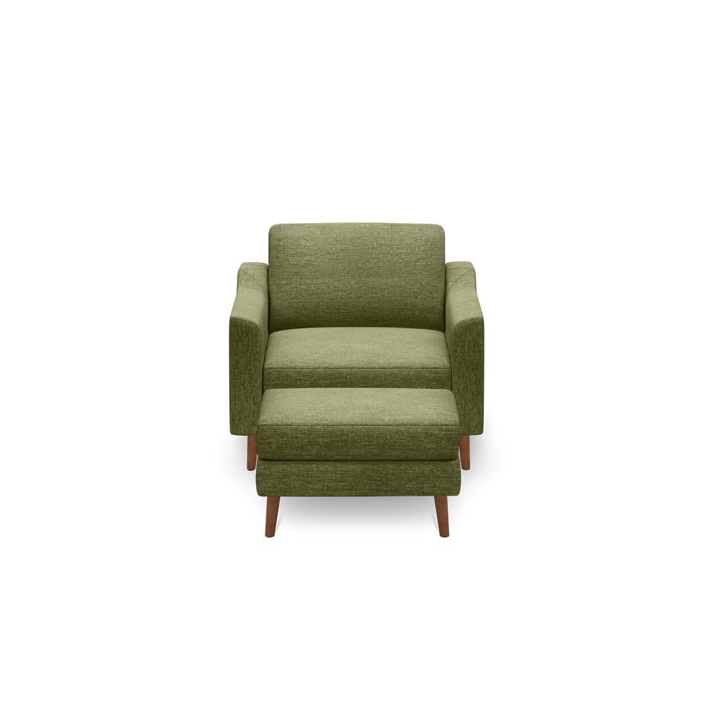 Green fabric armchair with matching cushioned ottoman and wooden legs, shown against a black background.