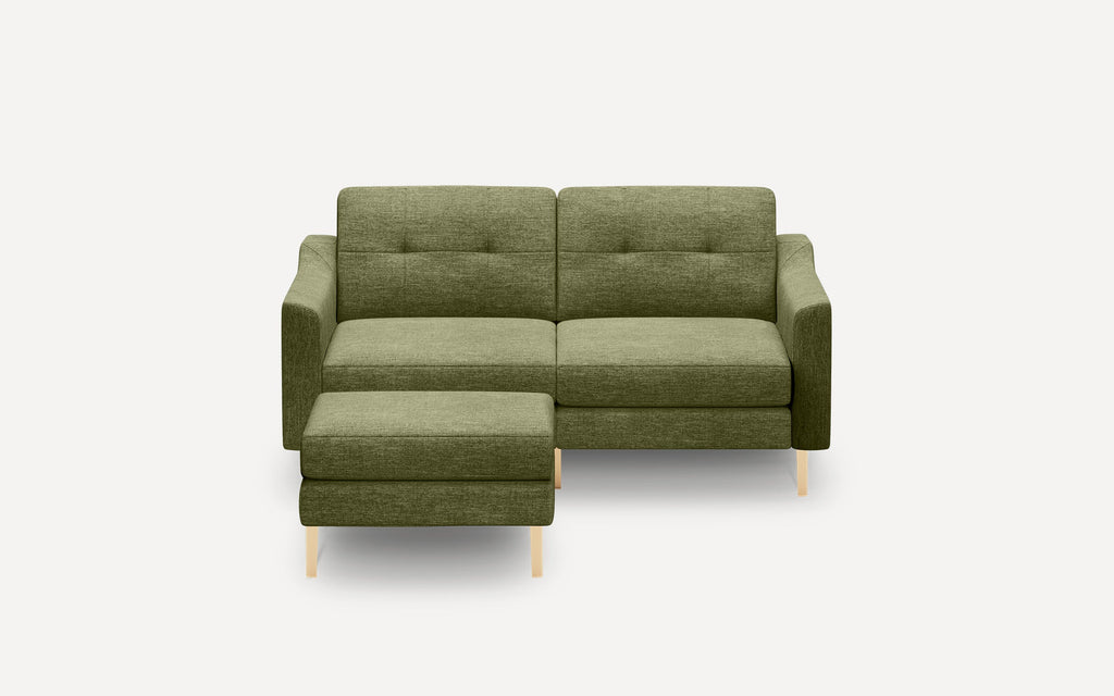 Modern olive green fabric sectional sofa with tufted back cushions and light wooden legs, including a matching ottoman.