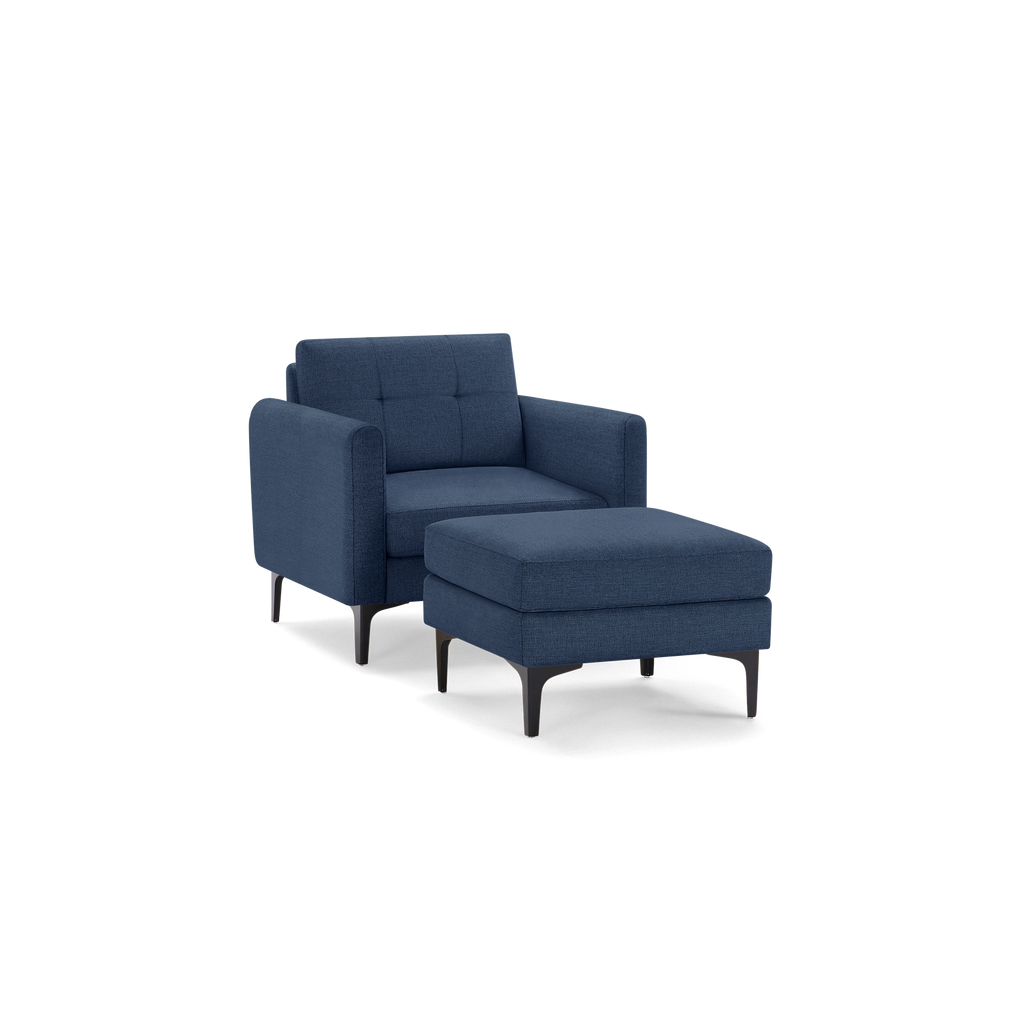 Modern navy blue upholstered armchair with matching cushioned ottoman and black angled legs, featuring a tufted backrest.