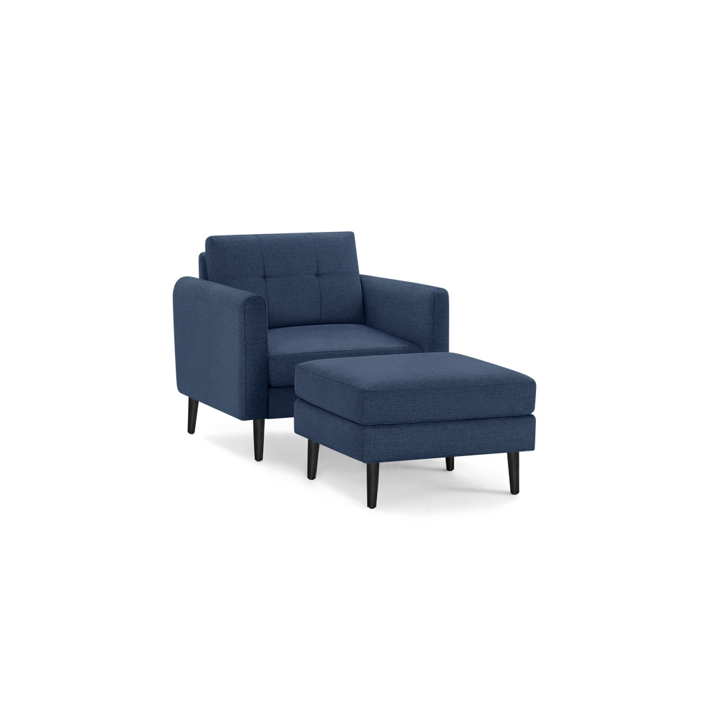 Modern navy blue fabric armchair with matching cushioned ottoman, featuring tufted backrest and black tapered wooden legs.
