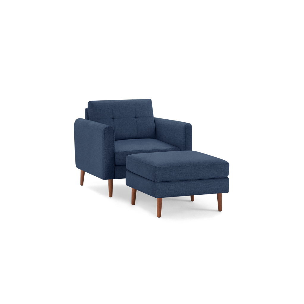 Modern navy blue upholstered armchair with matching ottoman, featuring wooden legs and tufted backrest design.