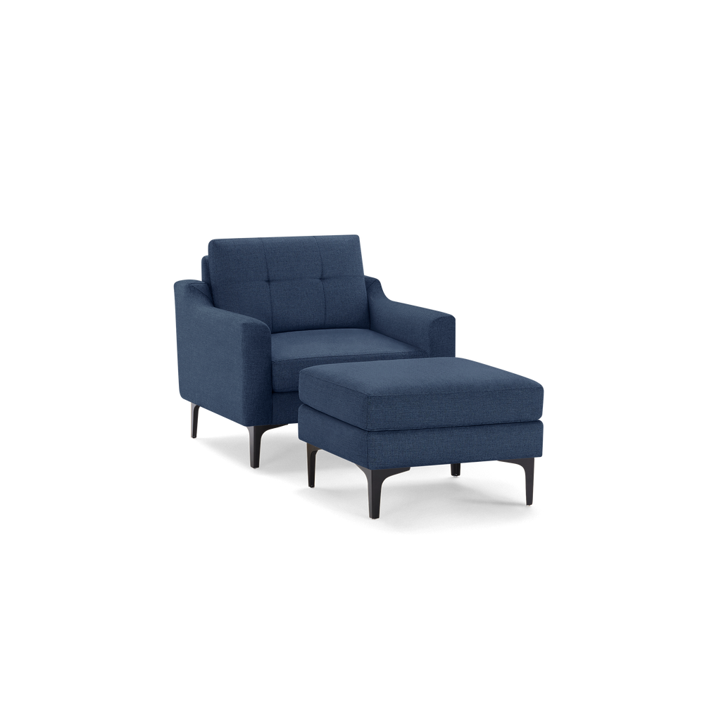 Modern navy blue armchair with tufted backrest and matching cushioned ottoman, both supported by slim black legs.