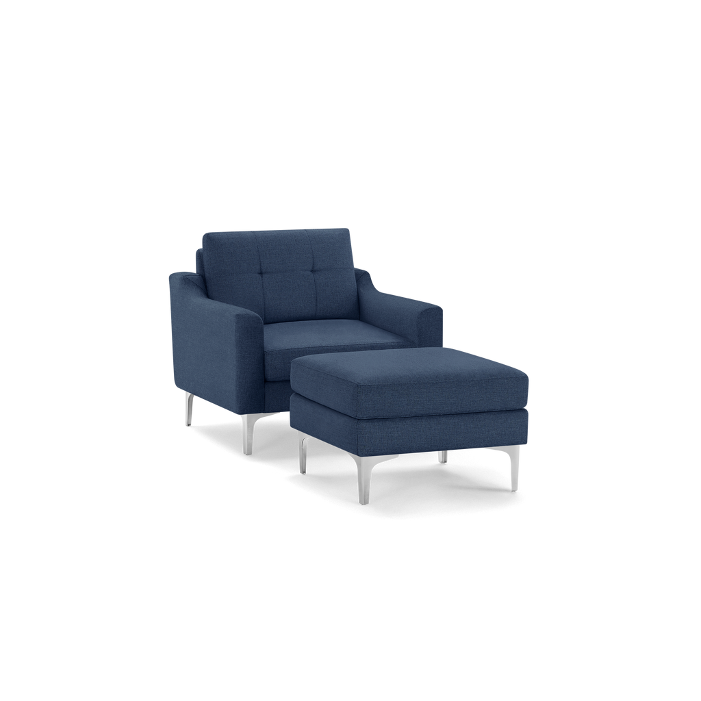 Modern navy blue upholstered armchair with matching ottoman, featuring tufted backrest and sleek silver metal legs.