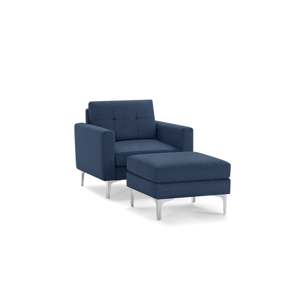 Modern navy blue armchair with matching cushioned ottoman, featuring silver metal legs and tufted backrest.