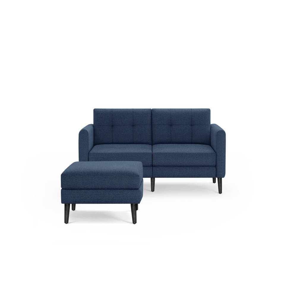 Modern navy blue fabric loveseat with matching cushioned ottoman, straight arms, tufted back, and black tapered wooden legs.
