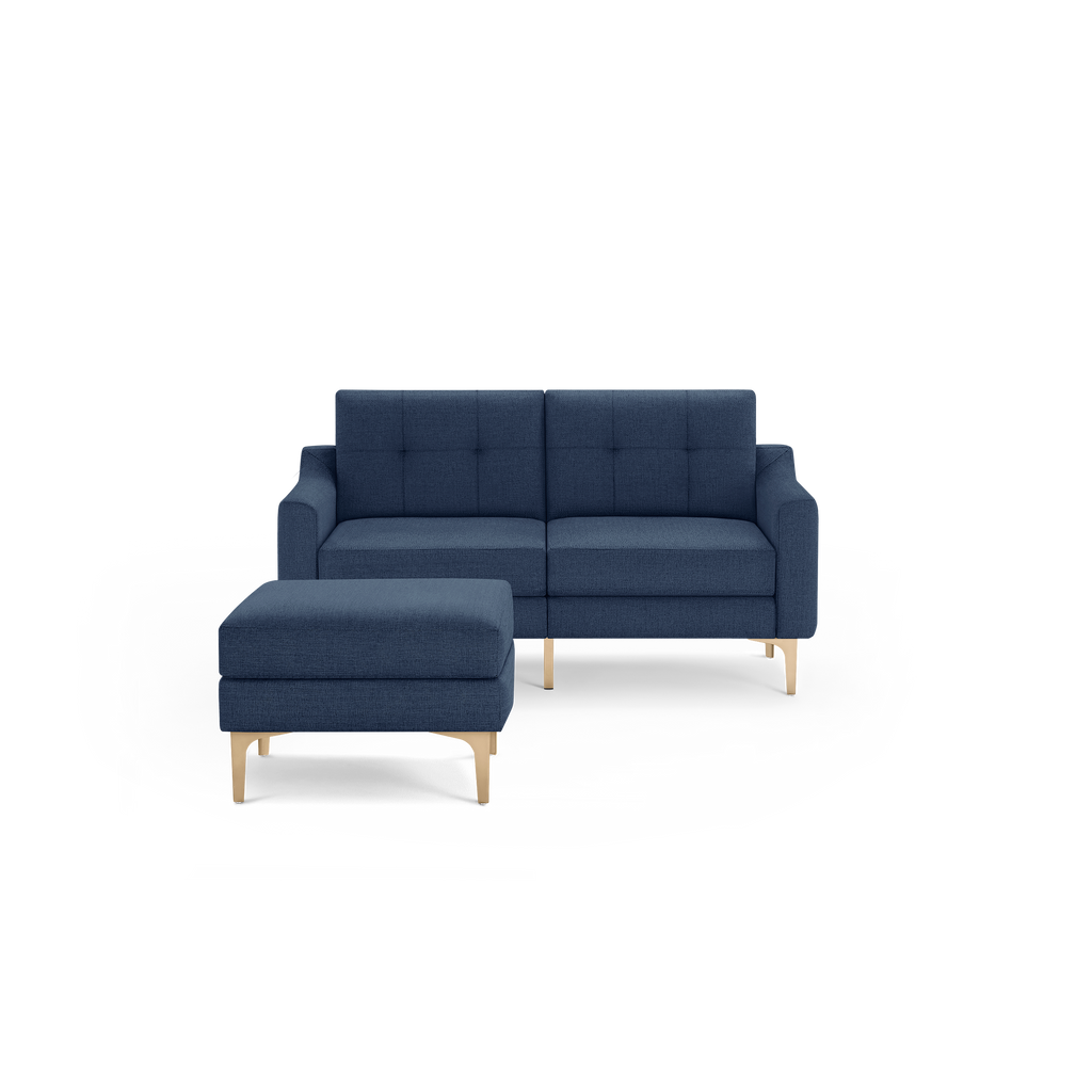 Modern navy blue fabric loveseat with tufted back cushions and wooden legs, paired with a matching ottoman on wooden legs.