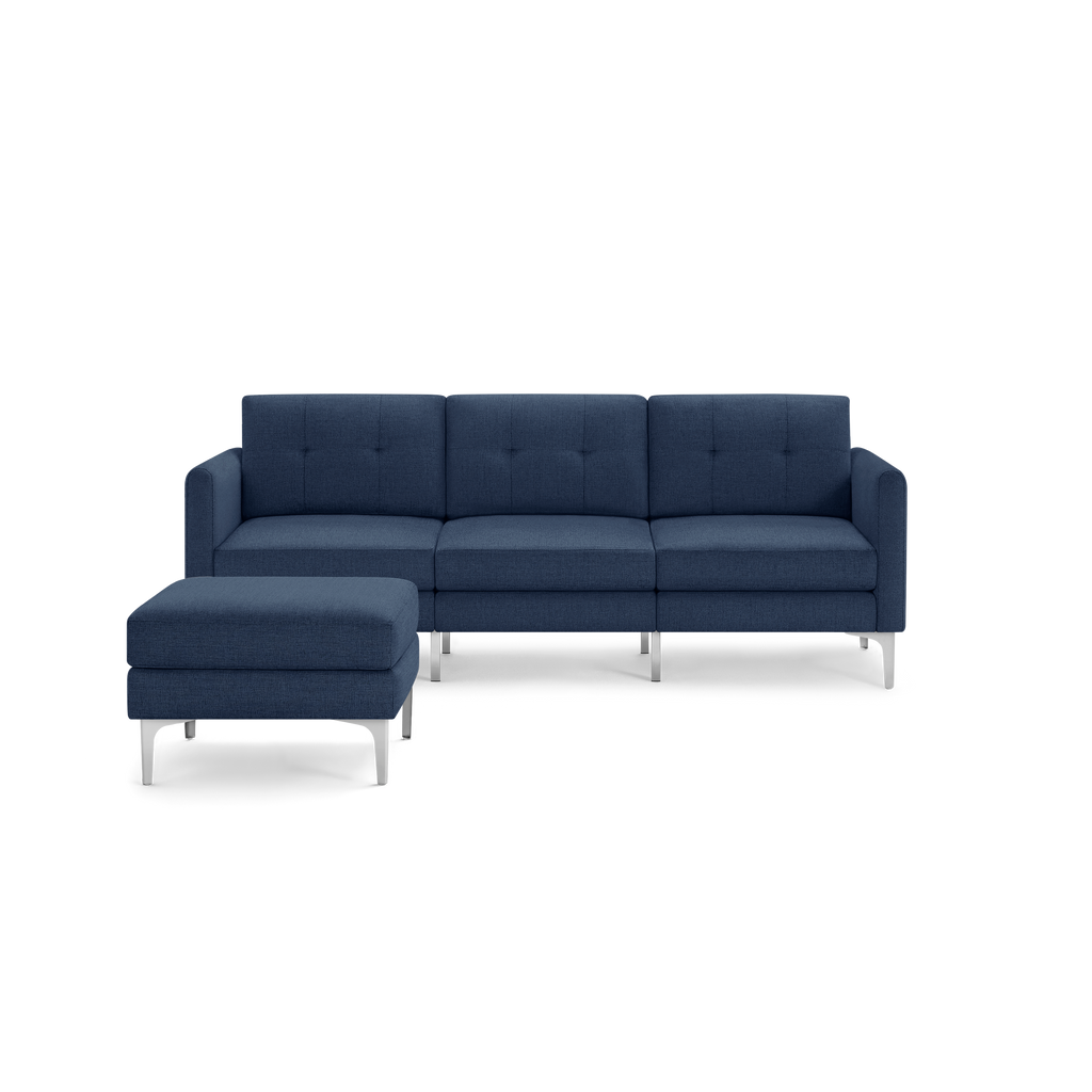 Modern L-shaped sectional sofa with deep blue fabric upholstery, tufted cushions, and sleek silver metal legs with matching ottoman.