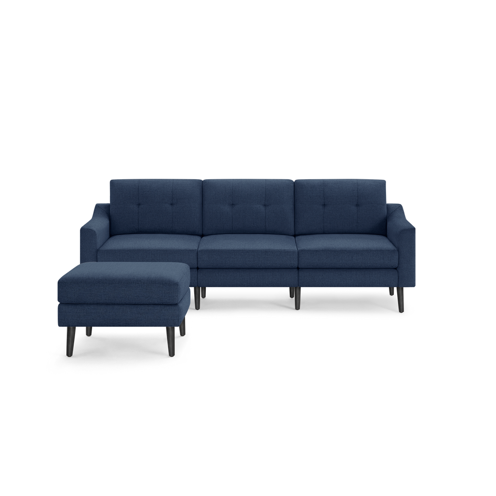 Modern navy blue fabric sectional sofa with tufted cushions and dark wooden legs, including a matching ottoman.