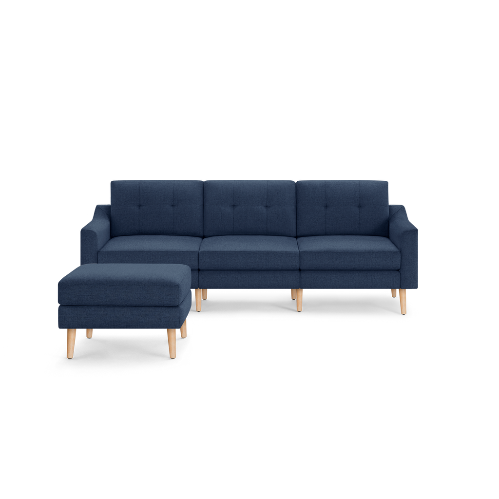 Modern navy blue sectional sofa with tufted cushions and light wooden legs, accompanied by a matching ottoman.