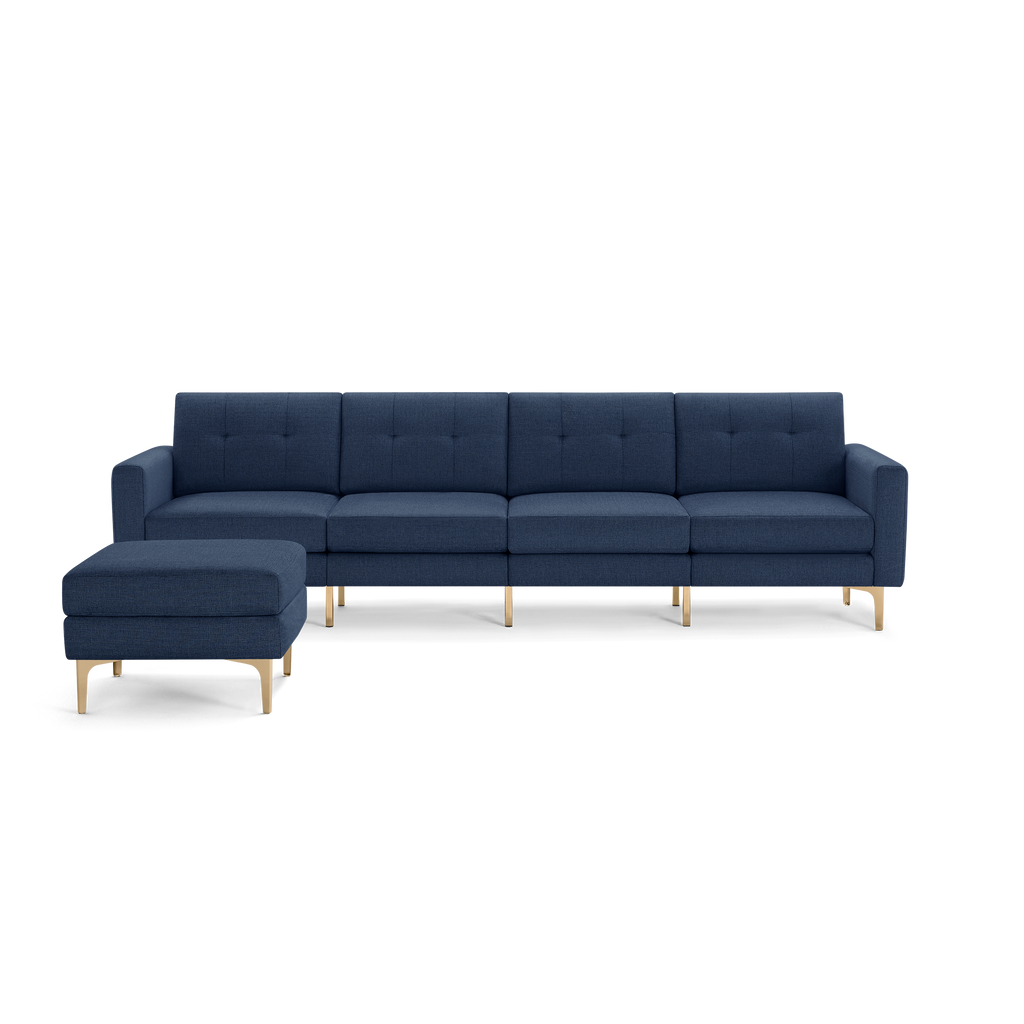 Modern navy blue sectional sofa with tufted cushions, straight arms, and light wooden legs, featuring a matching ottoman.