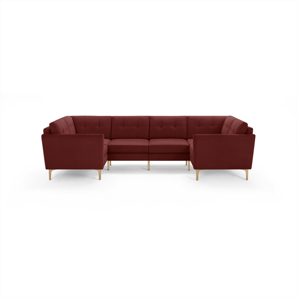Modern U-shaped sectional sofa upholstered in deep red fabric with tufted back cushions and slim wooden legs.