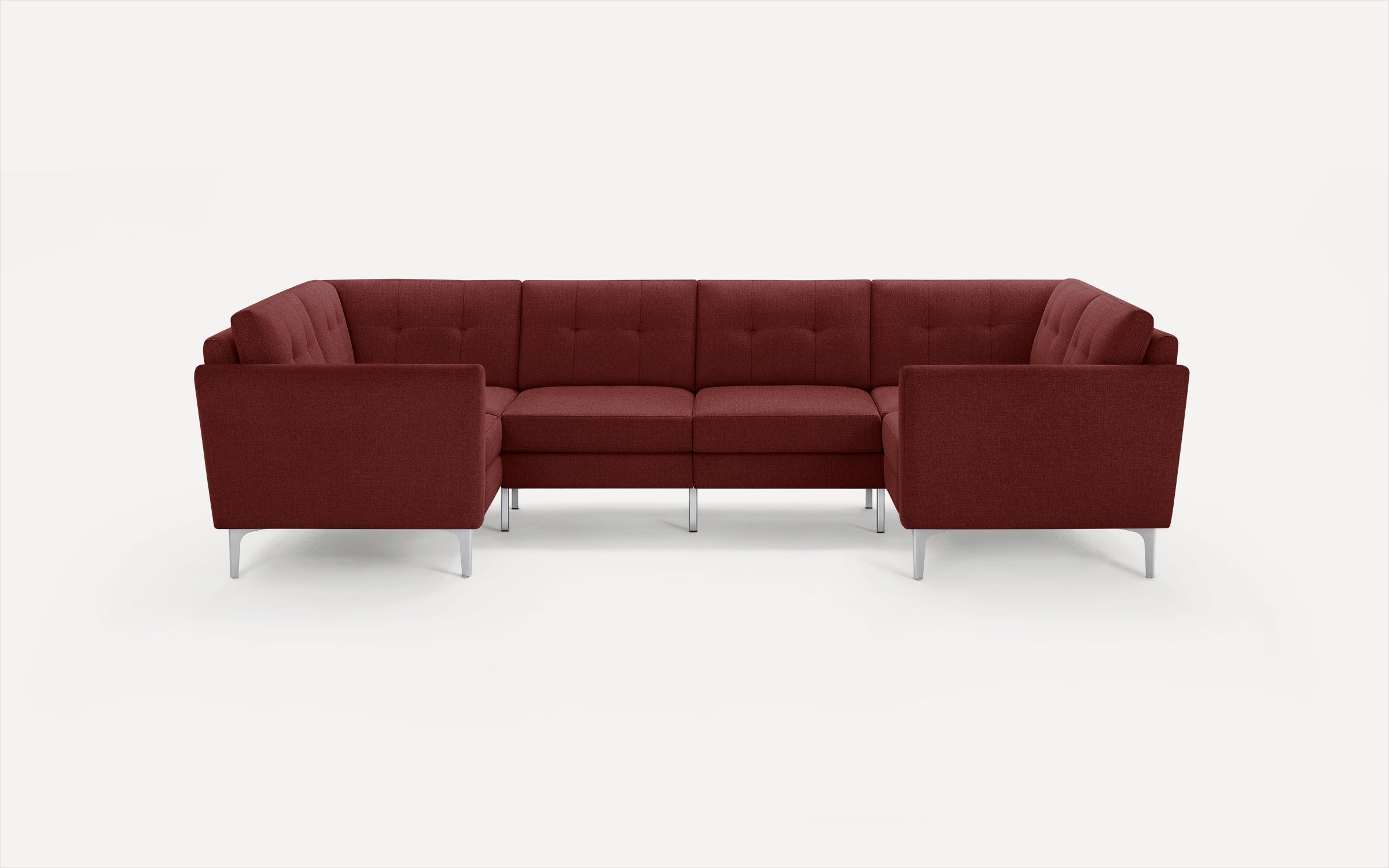 Modern modular sectional sofa in deep burgundy fabric with tufted back cushions, slim silver legs, and clean lines.