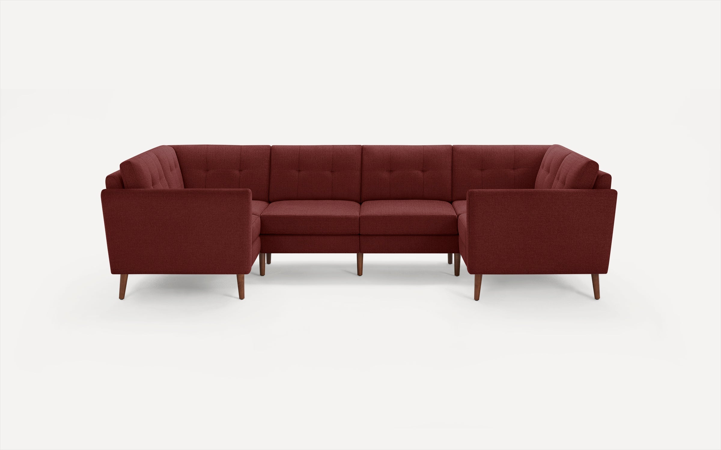Modern U-shaped sectional sofa in deep burgundy fabric with tufted back cushions and wooden tapered legs, shown on a white background.