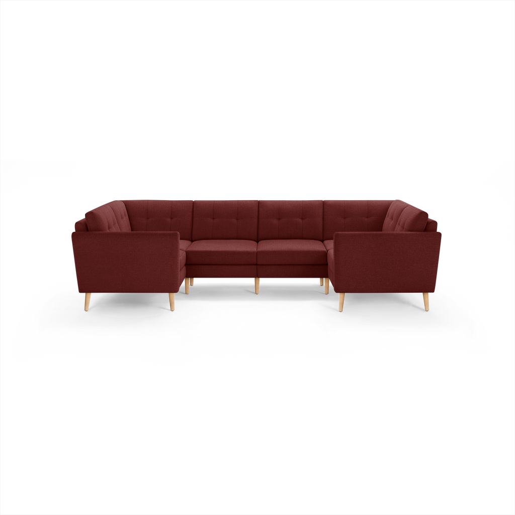 Large L-shaped sectional sofa in deep burgundy fabric with tufted cushions and light wooden legs.