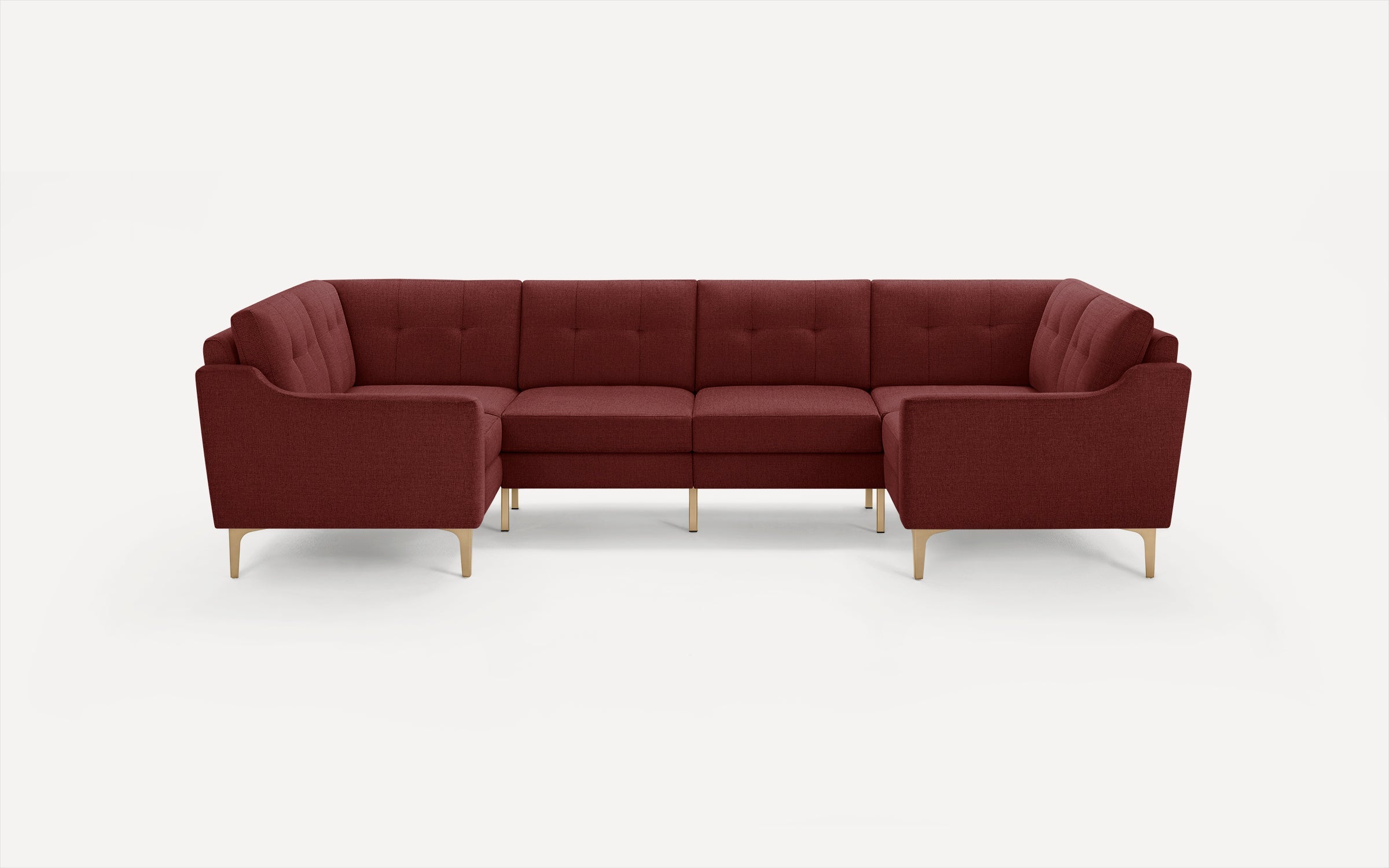 Modern U-shaped sectional sofa in deep red fabric upholstery with tufted back cushions and light wooden legs against white background.