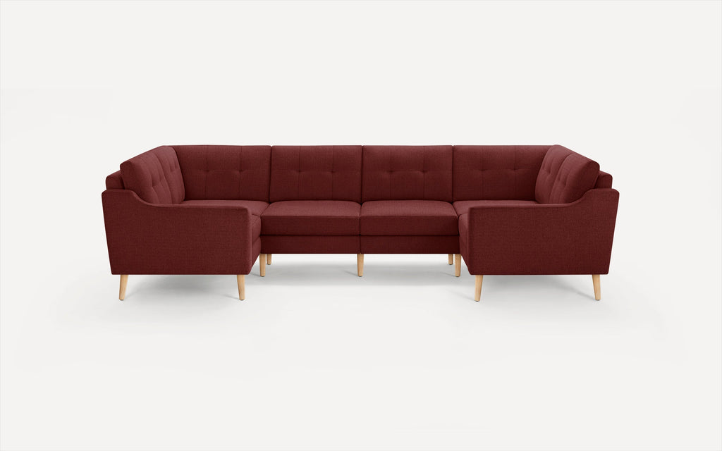 Modern L-shaped sectional sofa in deep red fabric with tufted cushions and light wooden legs, set against a white background.