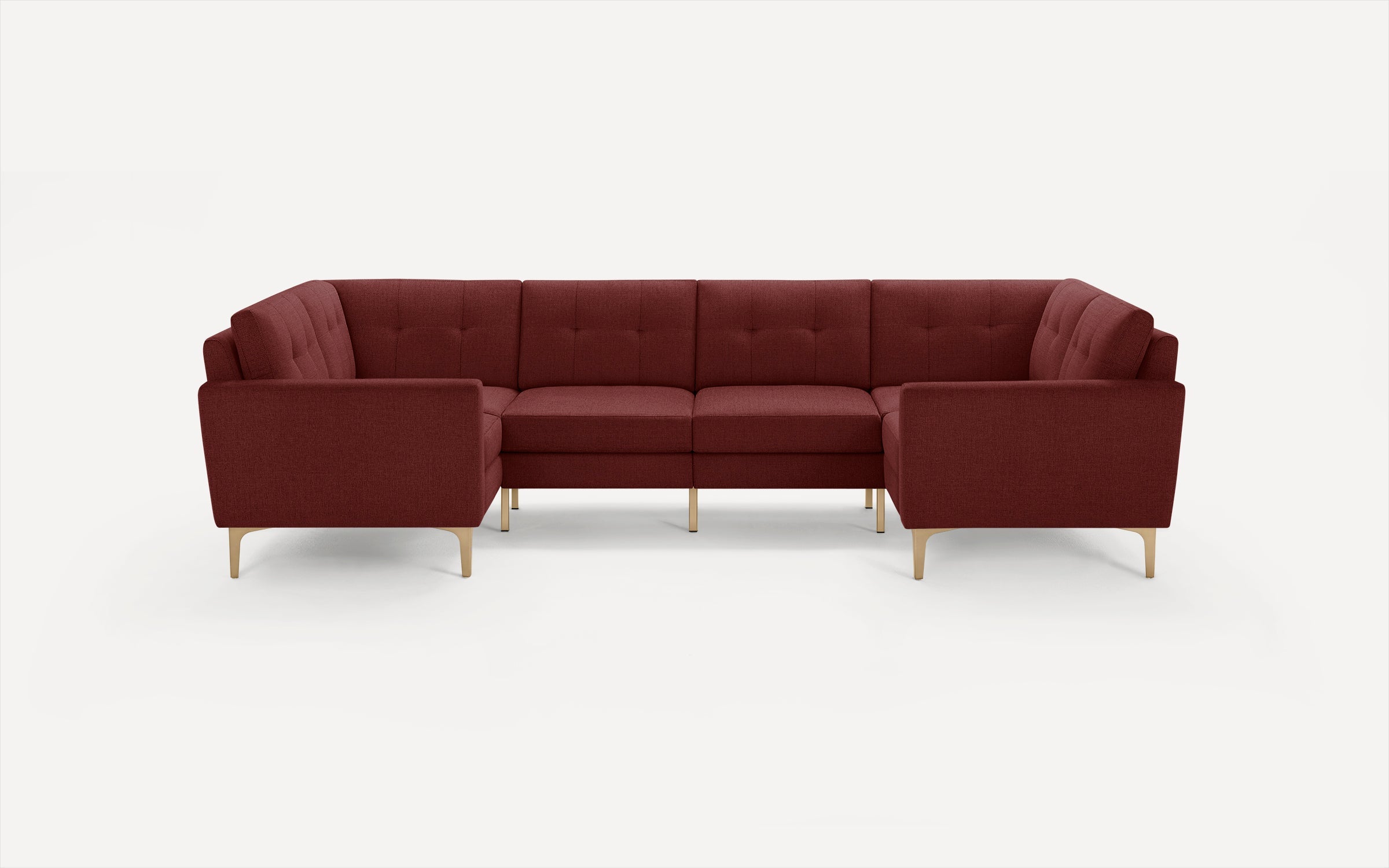 Modern U-shaped sectional sofa with deep red upholstery, tufted back cushions, and slim gold legs on white background.