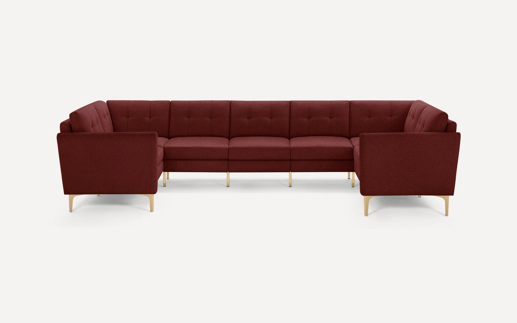 Modern U-shaped sectional sofa in deep burgundy fabric with tufted cushions and light wooden legs, designed for spacious seating.