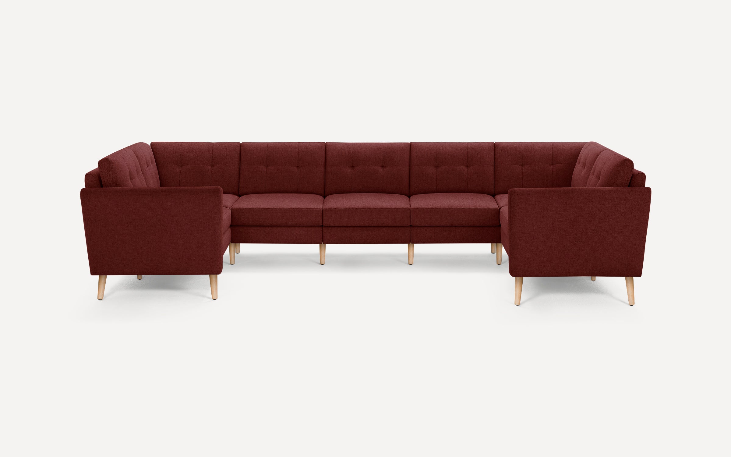 Modern U-shaped sectional sofa with deep red fabric upholstery, tufted back cushions, and light wooden legs on white background.