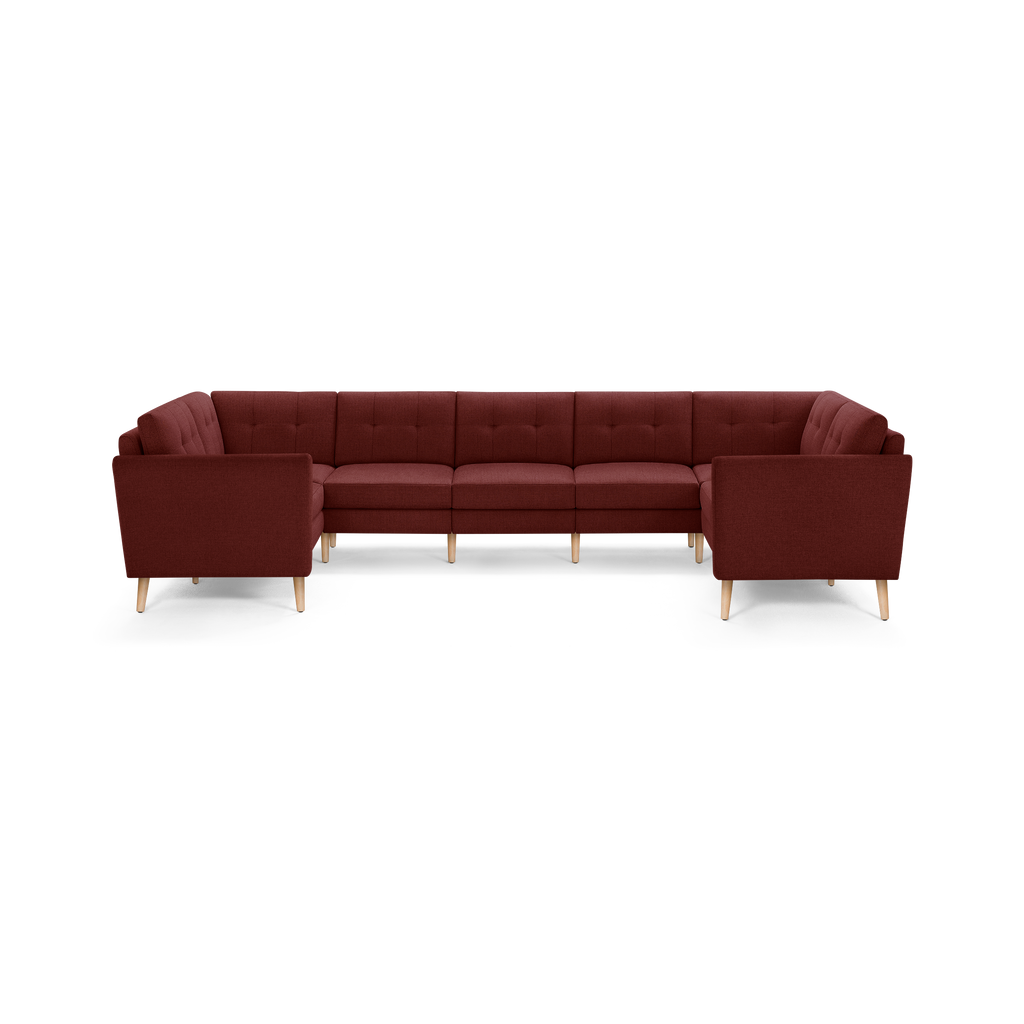 Large U-shaped sectional sofa in deep burgundy fabric with tufted back cushions and light wooden legs.