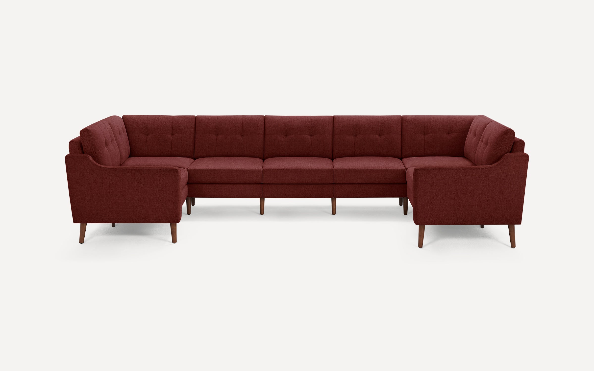 Modern U-shaped sectional sofa in deep burgundy fabric with tufted back cushions and wooden tapered legs.