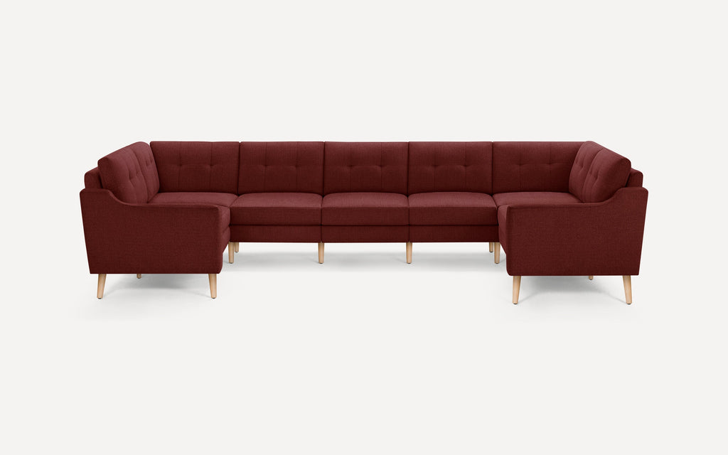 Large sectional sofa in dark red fabric with tufted back cushions and light wood tapered legs, designed for spacious living areas.