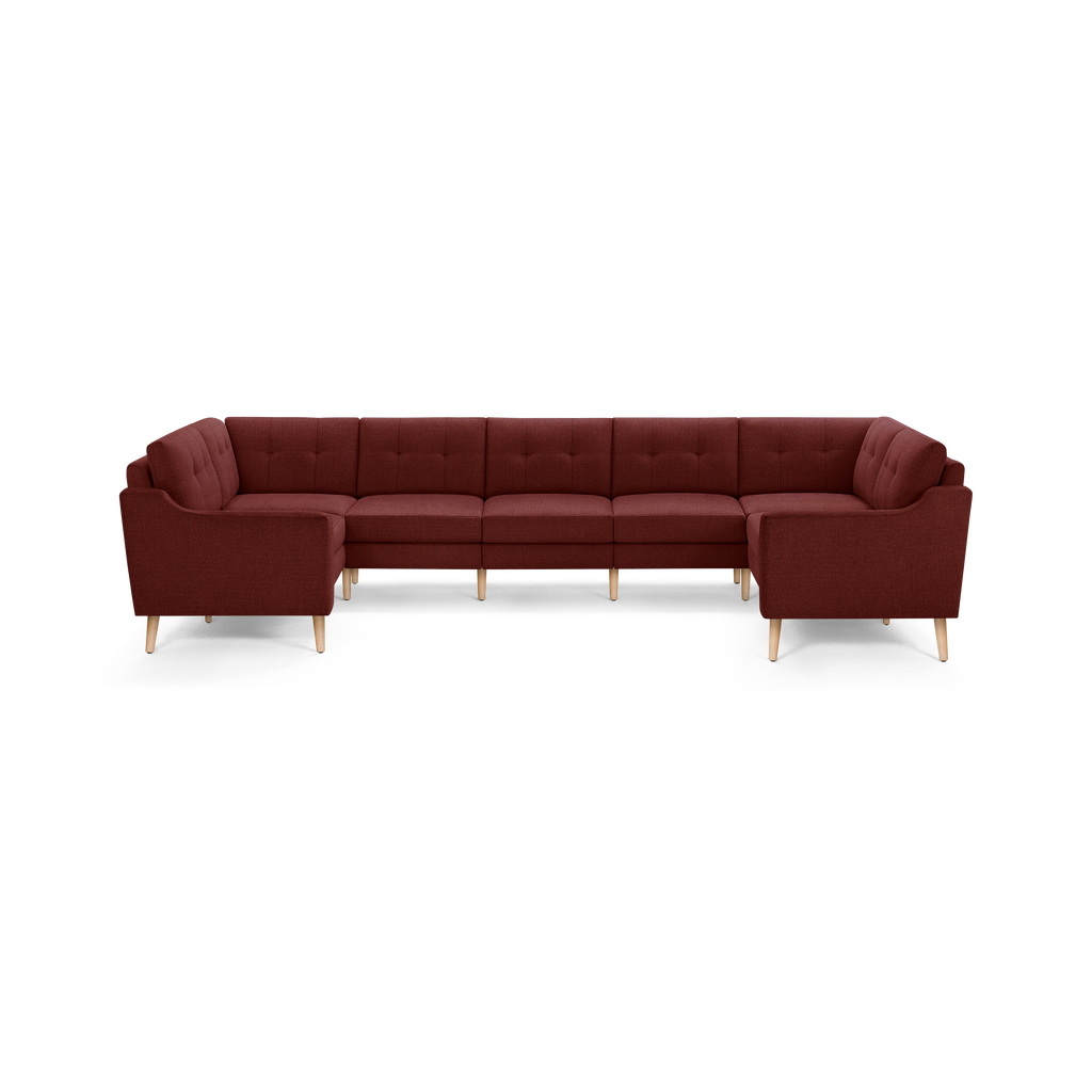 Large U-shaped sectional sofa with deep red fabric upholstery, tufted back cushions, and light wooden tapered legs.