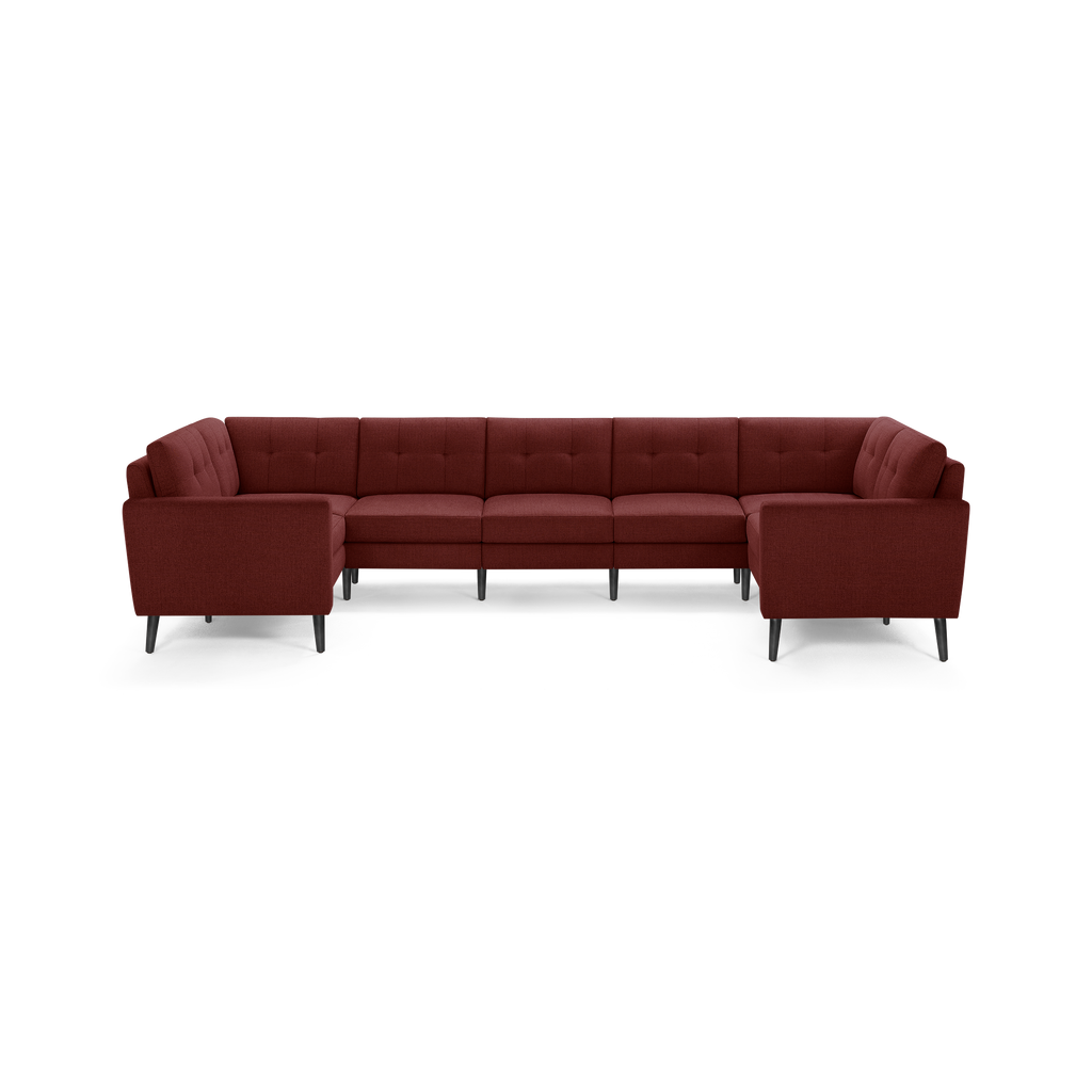 Large modern U-shaped sectional sofa upholstered in dark red fabric with tufted back cushions and slim dark legs.
