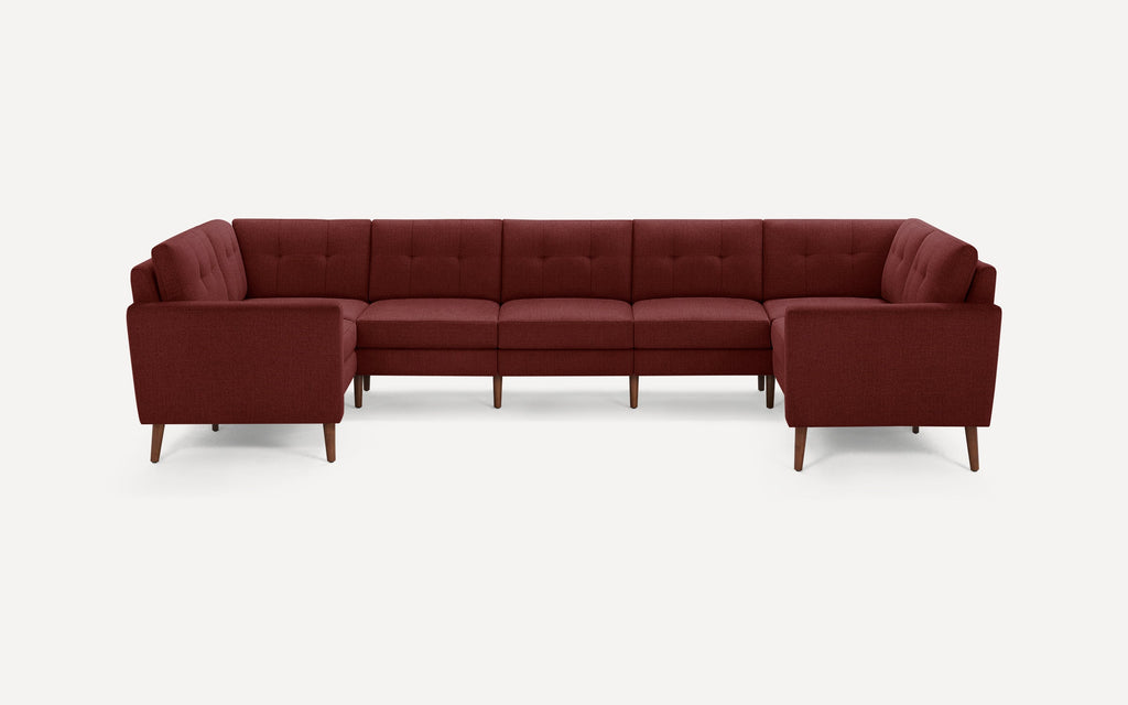 Large U-shaped sectional sofa with tufted back cushions, deep red fabric upholstery, and tapered wooden legs on a white background.