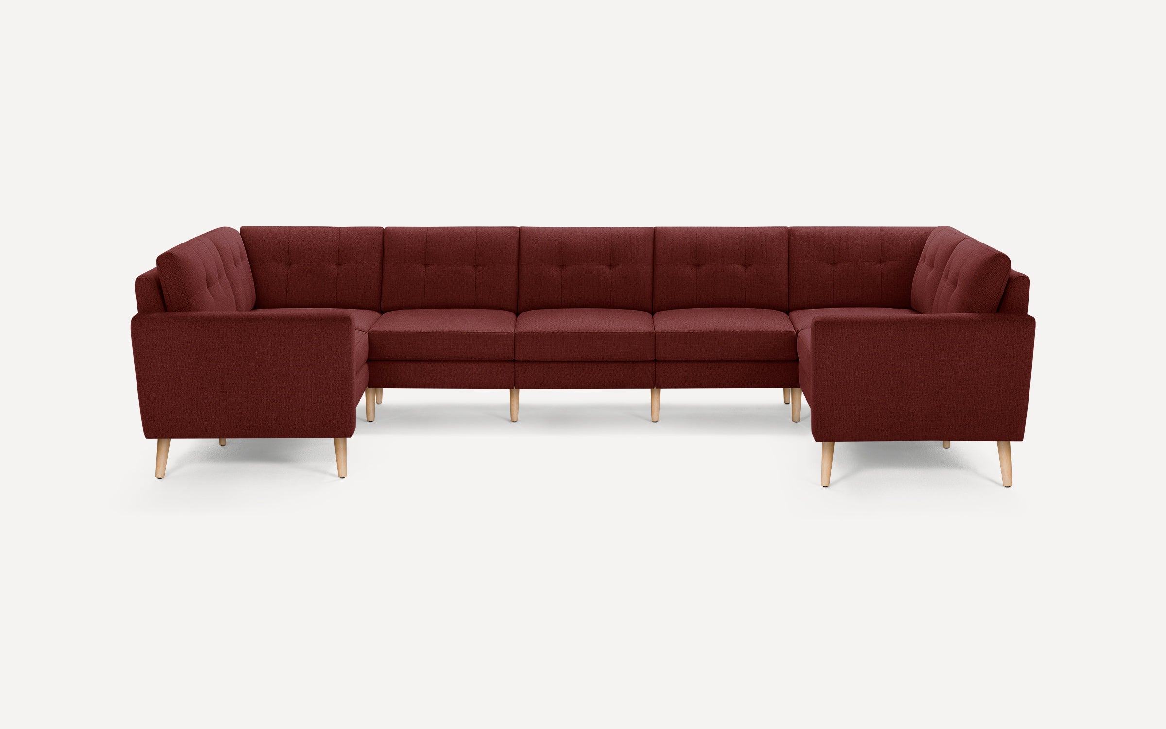 Large sectional sofa in a deep burgundy fabric with tufted back cushions and light wooden legs, designed for modern living rooms.