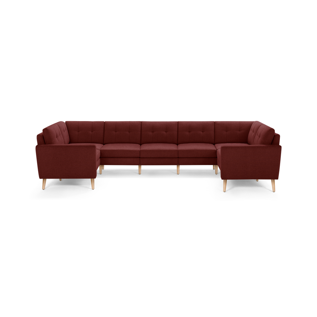 Large U-shaped sectional sofa with deep red fabric upholstery, tufted back cushions, and light wooden tapered legs.