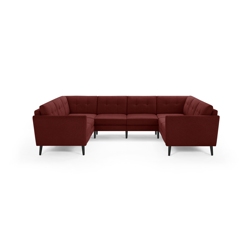 Large U-shaped sectional sofa in deep burgundy fabric with tufted back cushions and black tapered wooden legs.