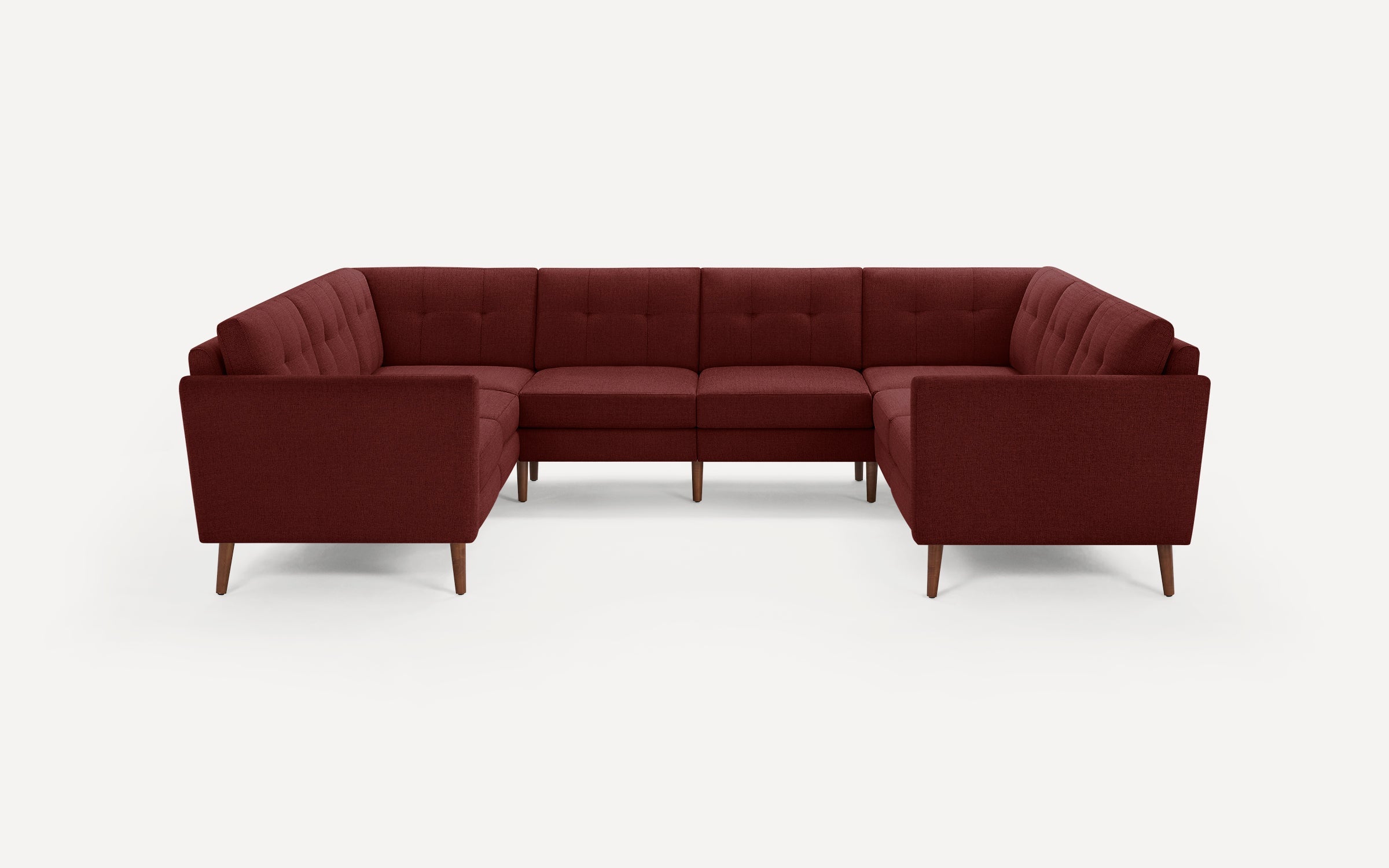 Mid-century modern U-shaped sectional sofa in deep burgundy fabric with tufted cushions and wooden legs, set against a plain white background.