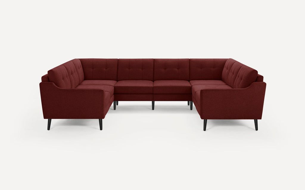 U-shaped burgundy fabric sectional sofa with tufted back cushions, slim black legs, and a modern mid-century design.