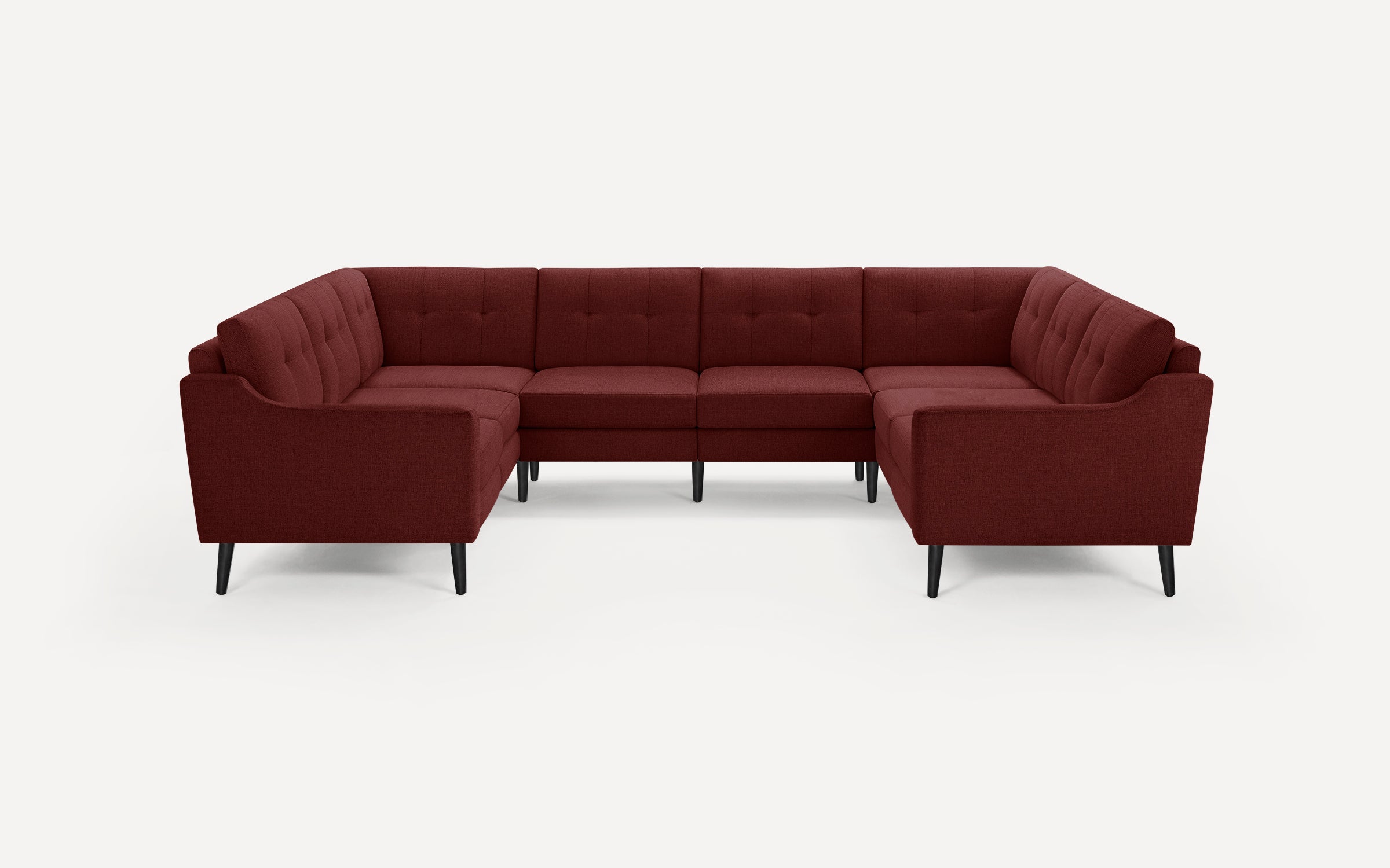 U-shaped burgundy fabric sectional sofa with tufted back cushions, slim black legs, and a modern mid-century design.