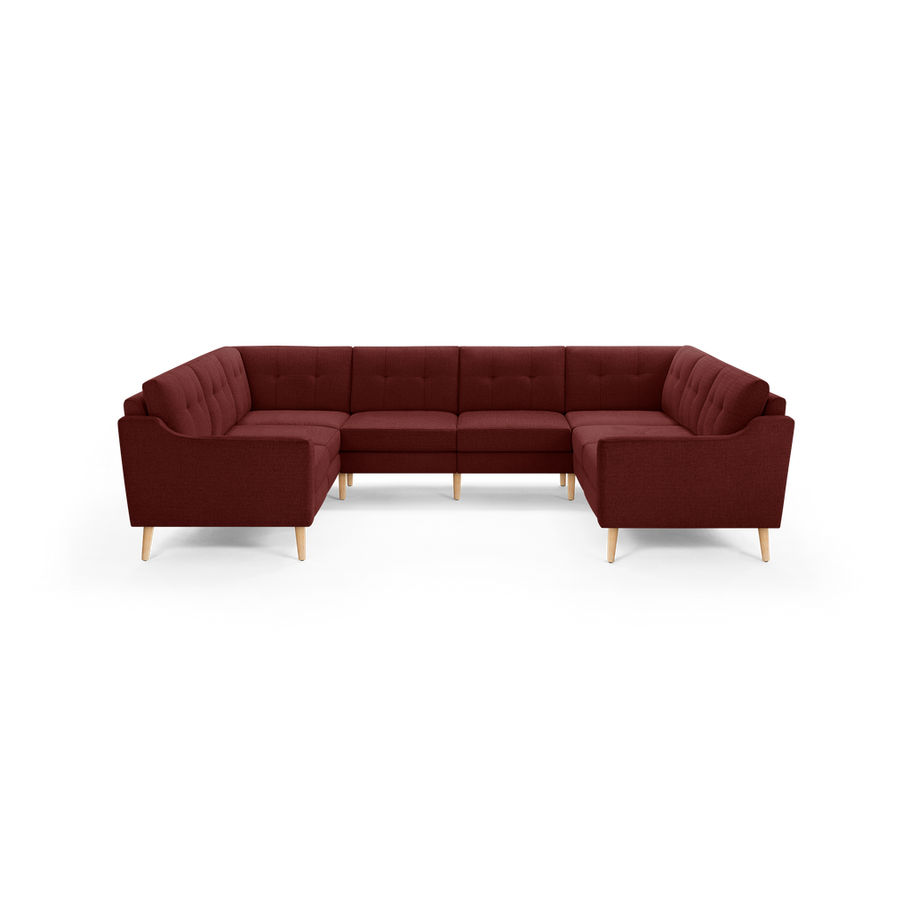 Large U-shaped sectional sofa upholstered in deep red fabric with button-tufted back cushions and light wooden legs.