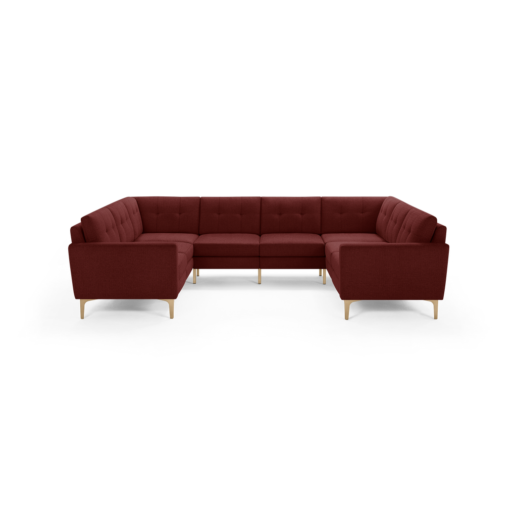 Modern U-shaped sectional sofa in deep burgundy fabric with tufted back cushions and light wooden legs.