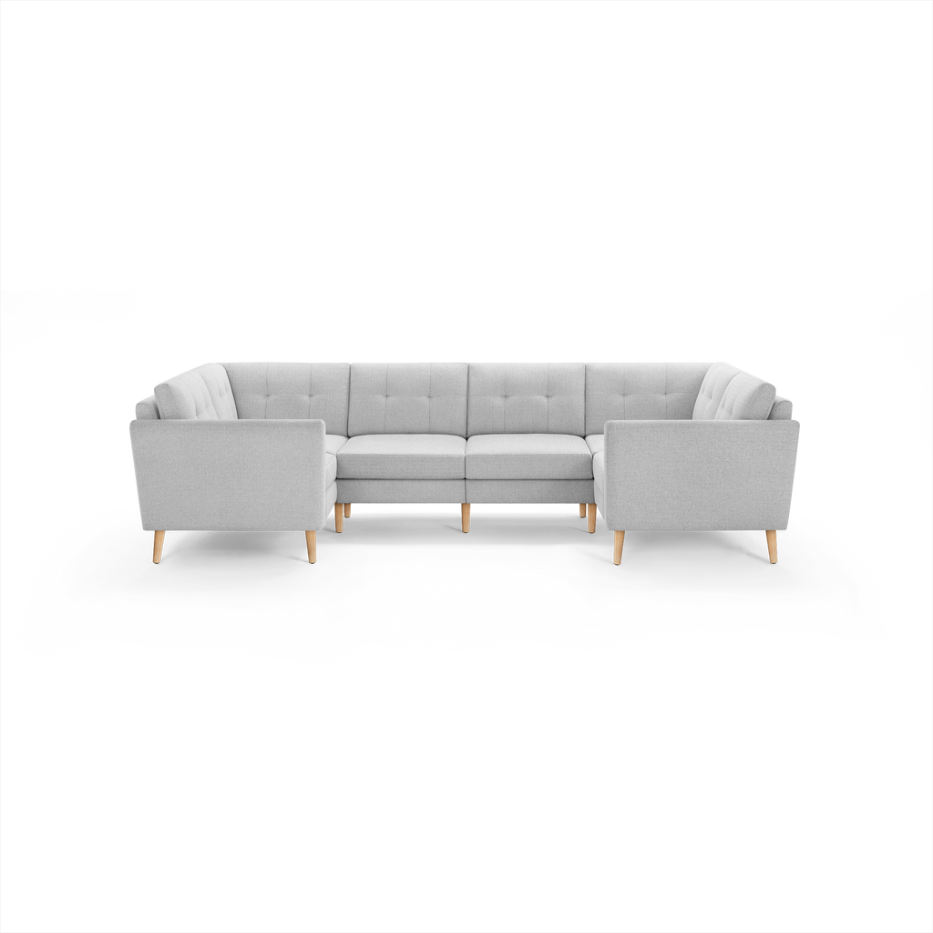 Light gray fabric sectional sofa with wooden legs, tufted back cushions, and modern, clean-lined design.