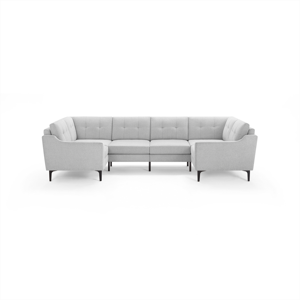 Light gray fabric U-shaped sectional sofa with tufted back cushions and slim black legs, modern design.