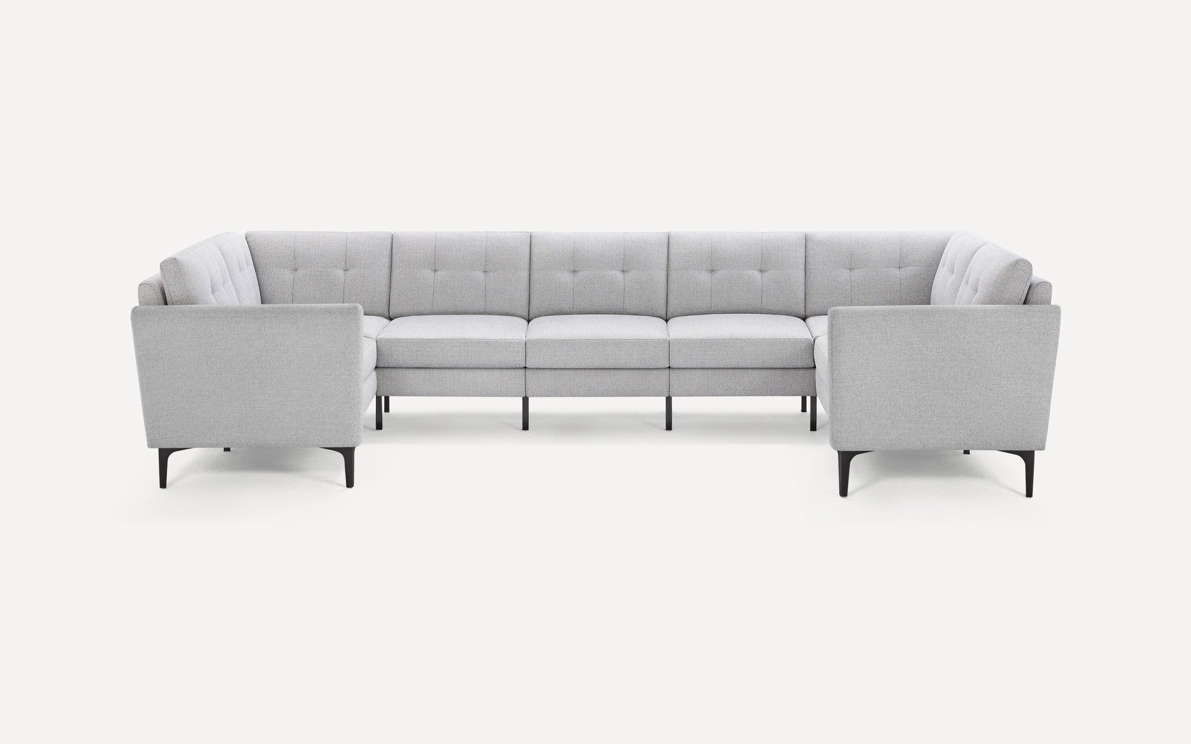 Light gray fabric U-shaped sectional sofa with tufted cushions and slim black legs, on white background.